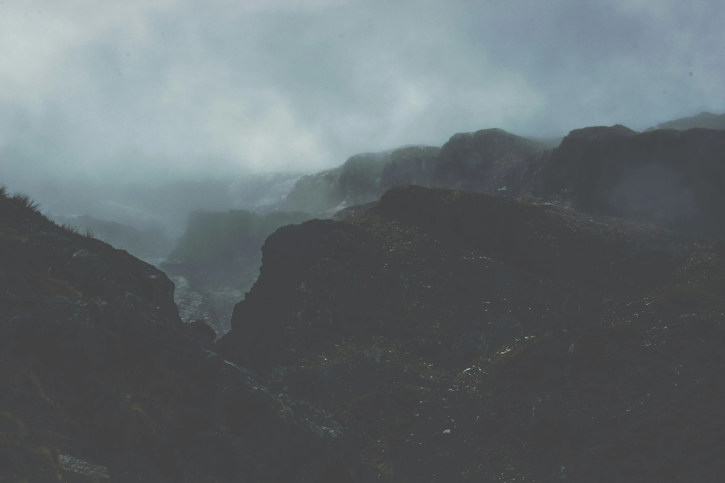 the mountains are covered in clouds as a person on a horse rides them