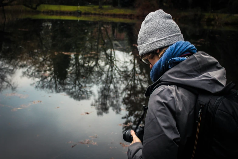 a person standing in front of water holding a camera