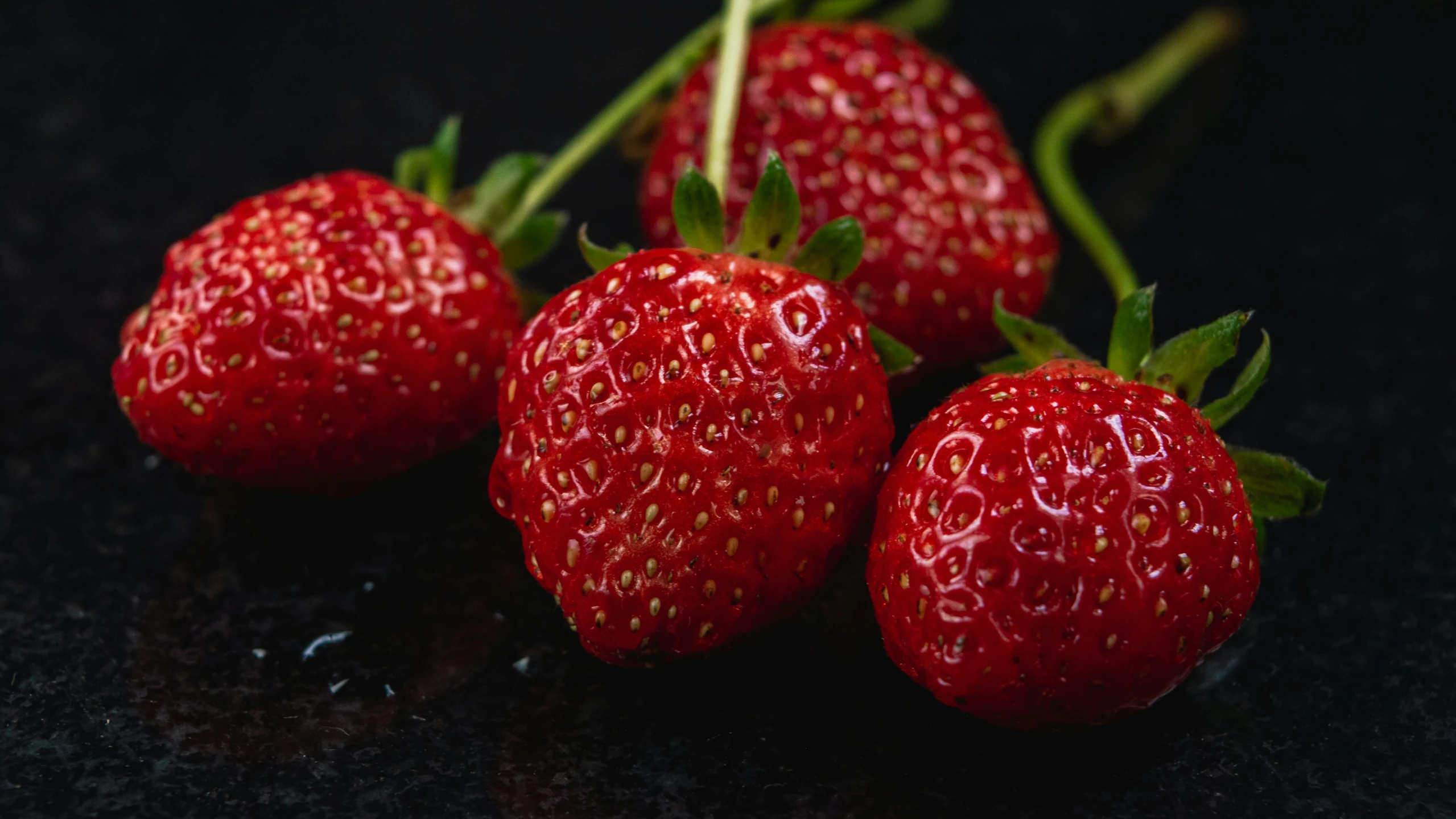 three very ripe strawberries sitting in a row