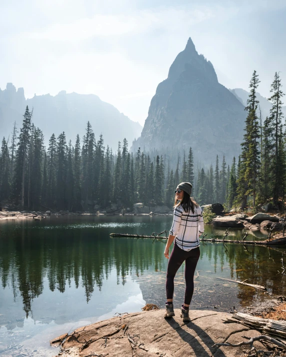 woman on the shore near water looking at trees