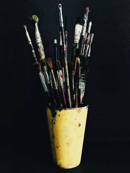 a yellow container with lots of paint brushes in it
