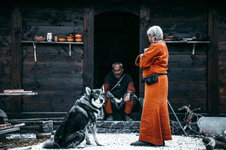 a man standing next to a woman with a large dog sitting on the ground