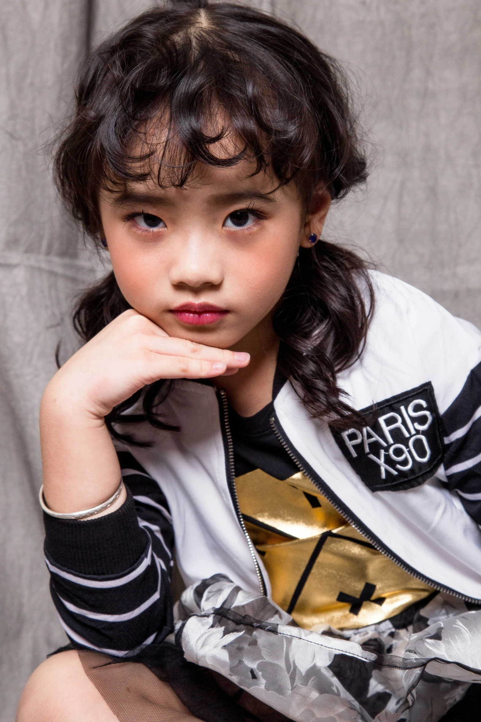 little girl sitting on a chair with her hand resting on her chin