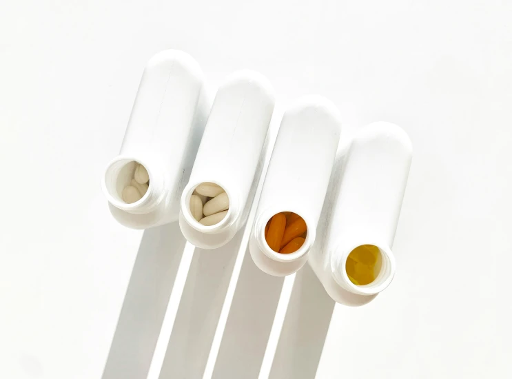 three different white tubes on a table with pills