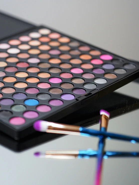 a makeup palette, two blue brushes and three pink and blue nail polish bottles