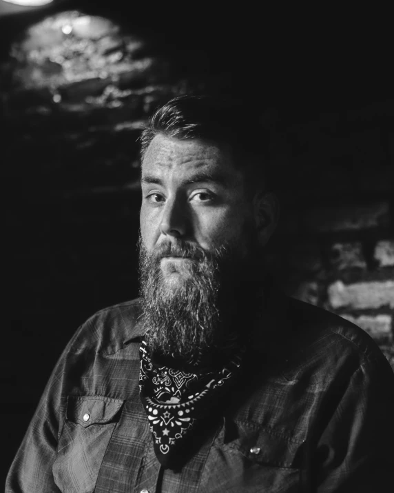 a man with a long beard standing by some bricks