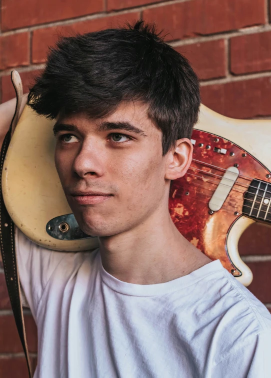 the young man has a guitar leaning against his head