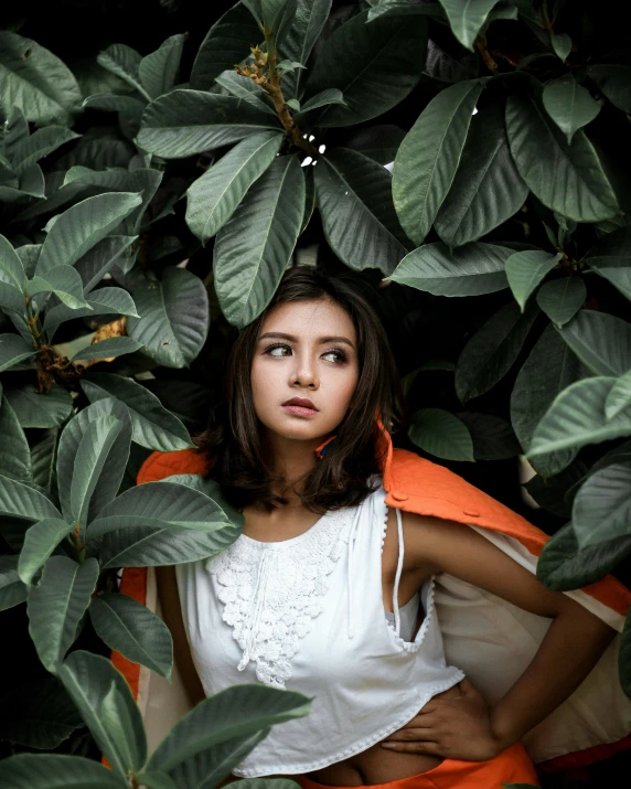 a woman poses for the camera beneath foliage