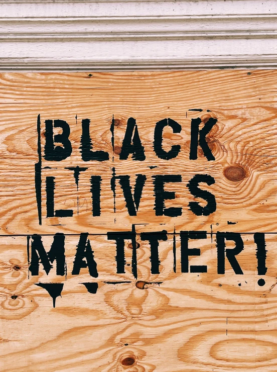 a wooden plank with black lives and text on it