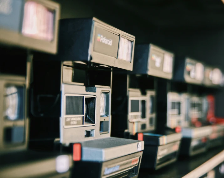 several different old cameras lined up on the shelf