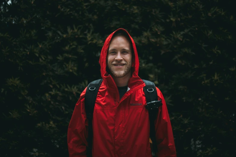 a man in a red jacket and hood smiling