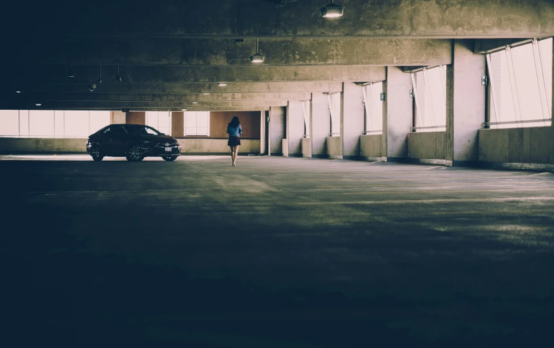 black car parked in parking spot with person in background