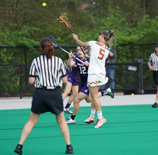 a couple of young ladies playing a game of lacrosse