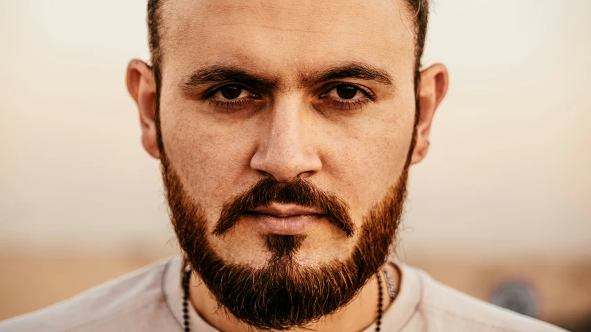 a close - up of a man with beard and a religious necklace