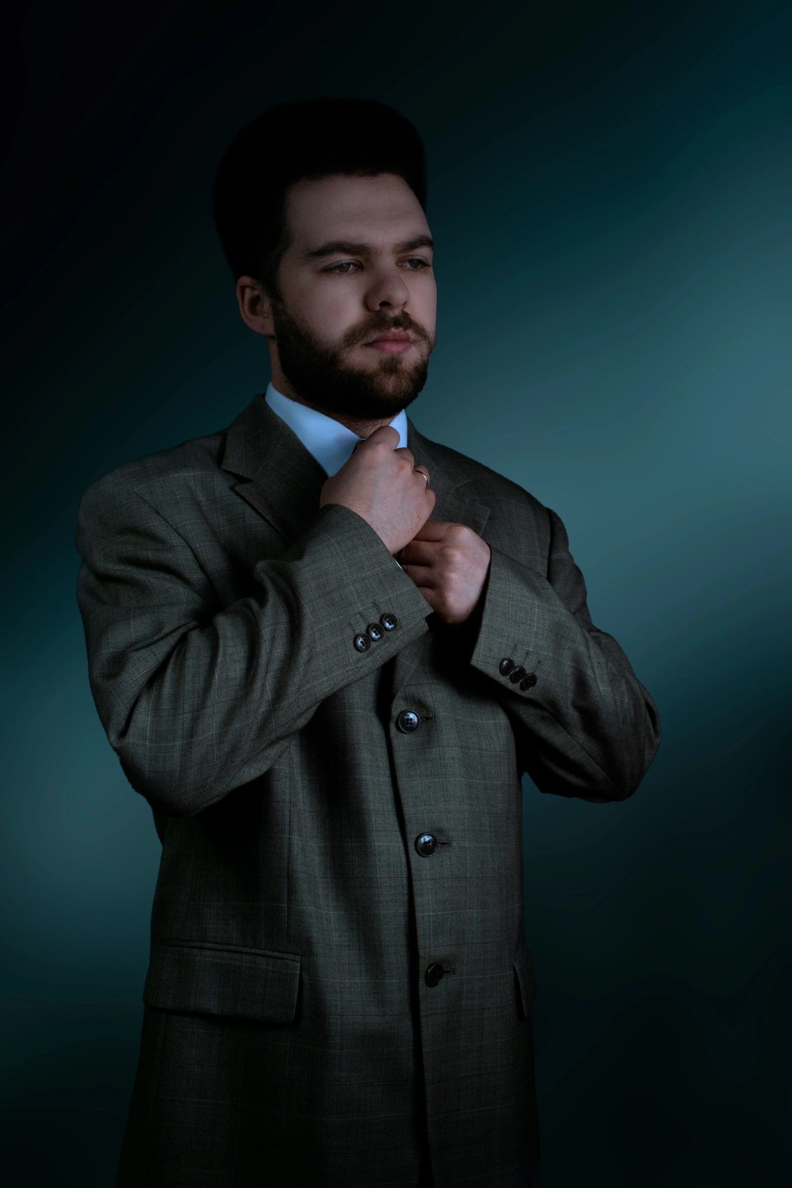 a man is straightening his tie in a dark room