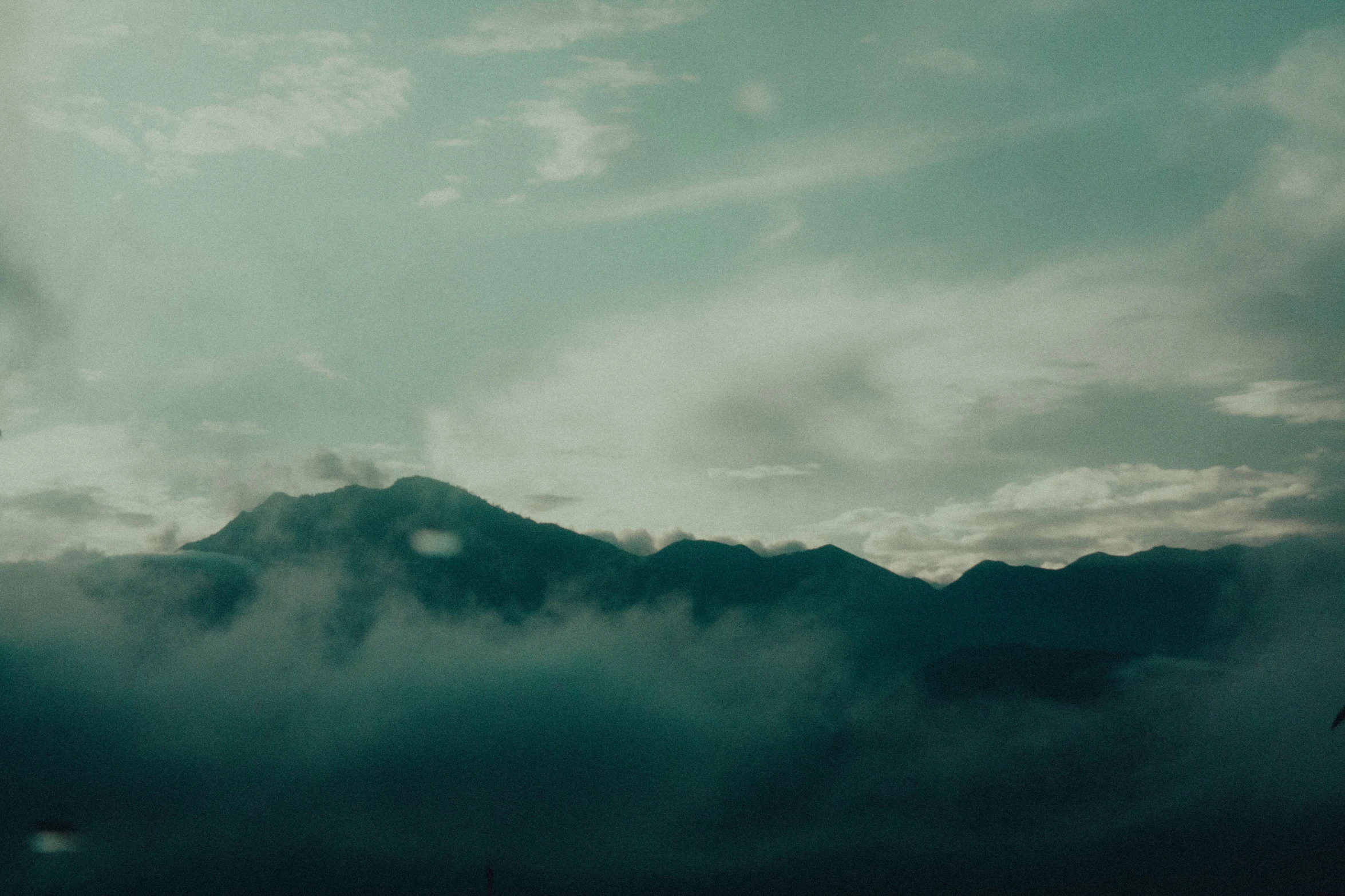 some clouds in the sky behind mountains