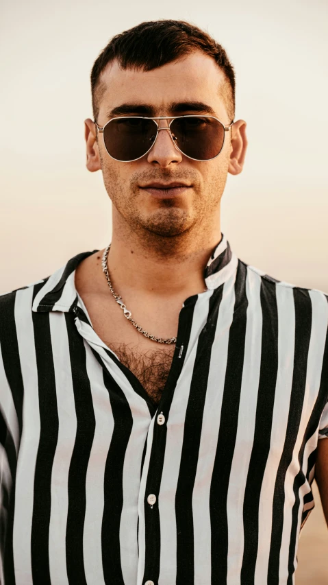 a man wearing a striped shirt and sun glasses