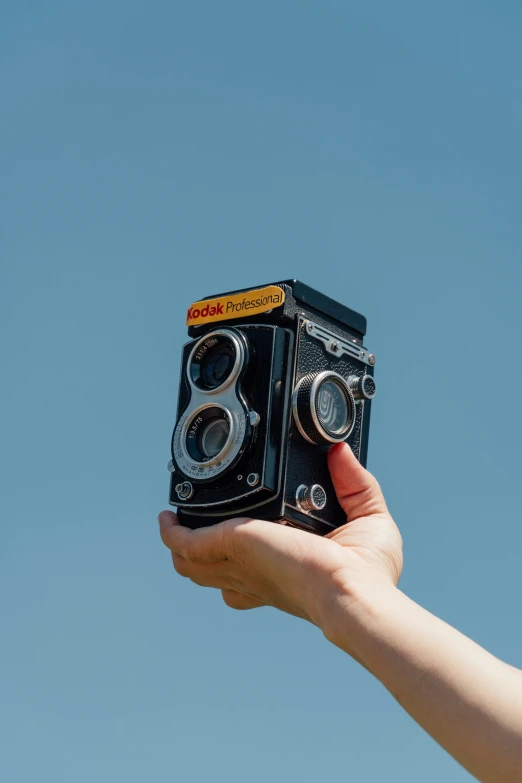 a hand holding up a camera with two lens