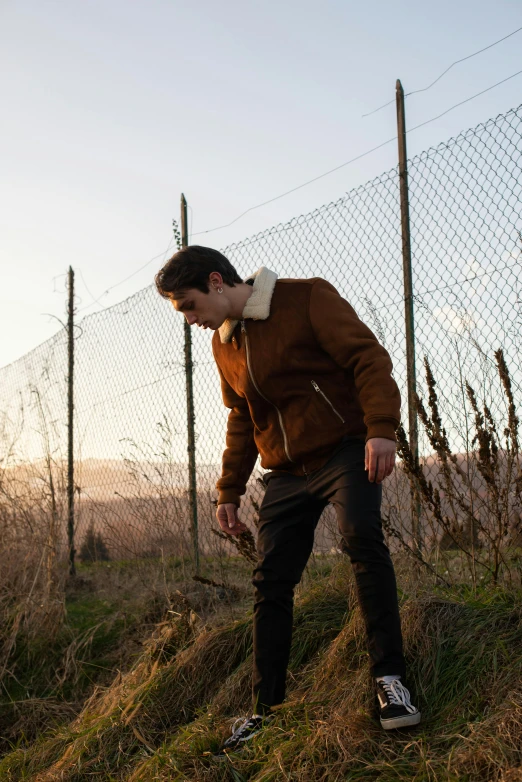 the young man is leaning against a wire fence