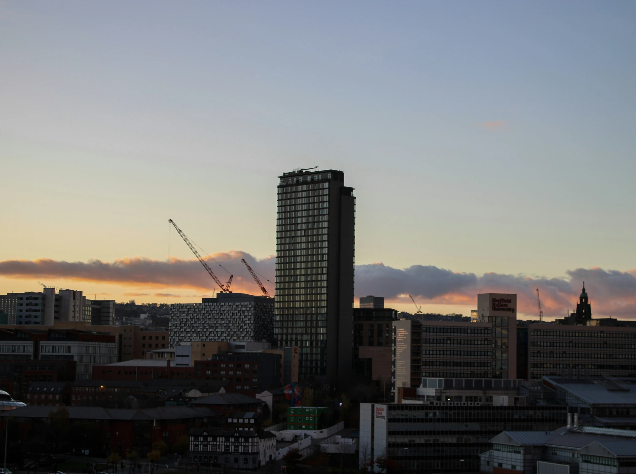 buildings and sky scrs in the distance with a pink sky behind them