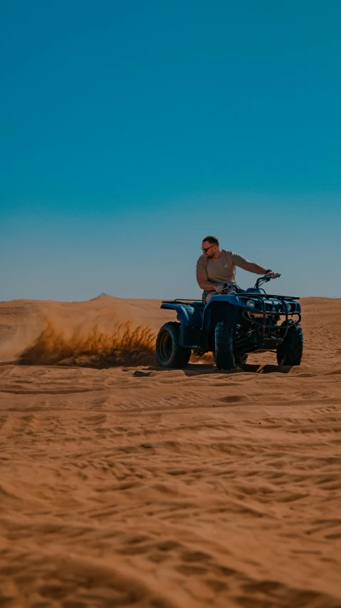 a man riding on the back of a blue four wheeler