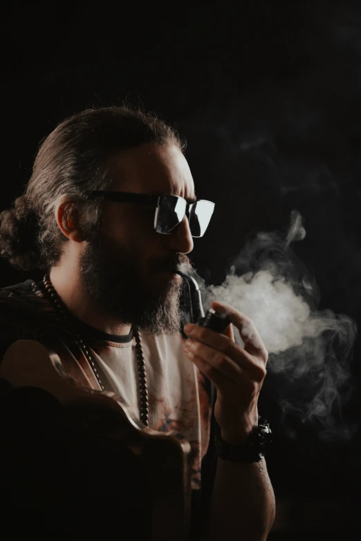 a man smoking an electronic cigarette in the dark