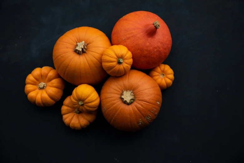 orange pumpkins and an apple, against black background