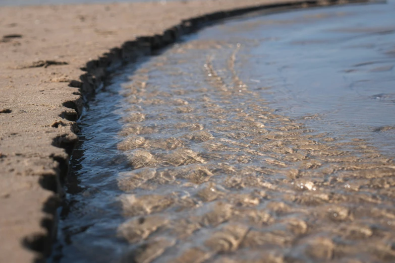 a picture of the side of some water on a beach