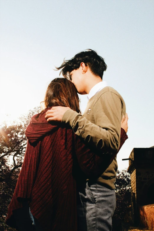 a woman kissing on the head of a man