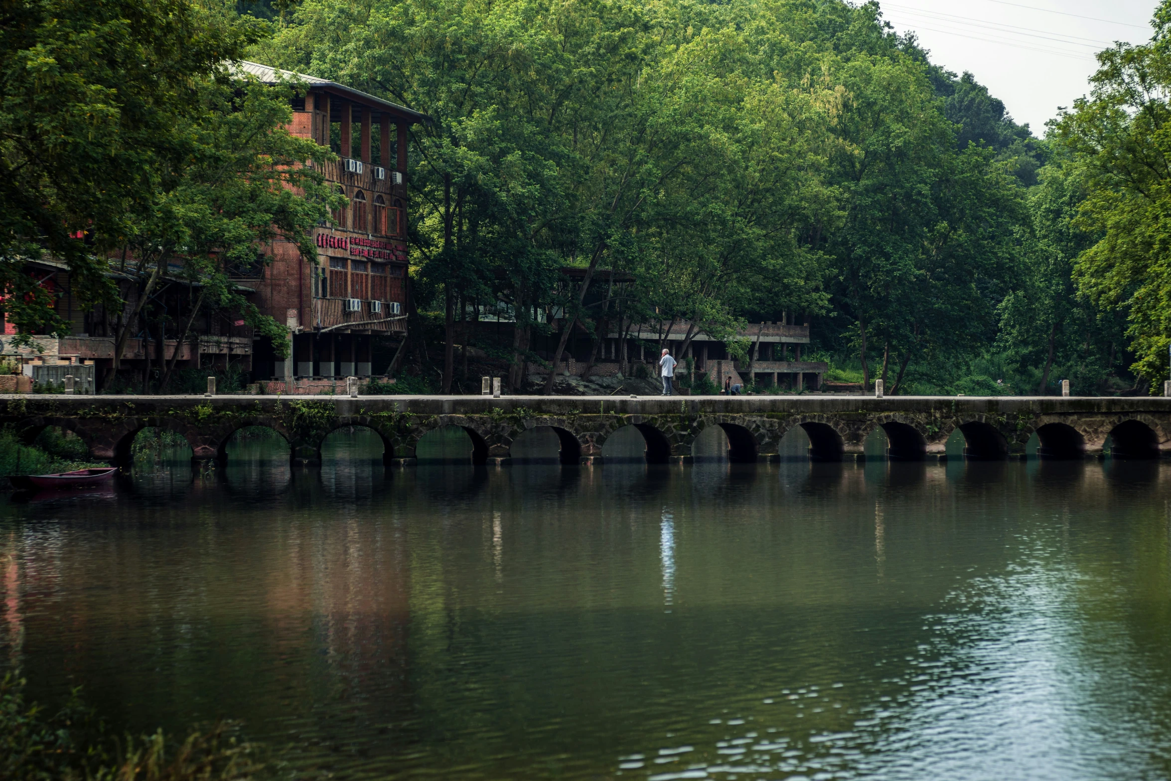 a bridge on a river with a row of trees in the background