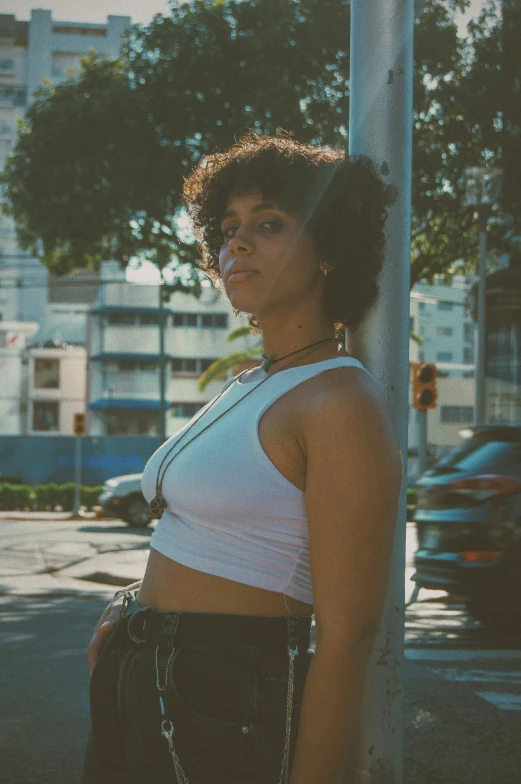 a woman standing by a pole looking into the camera