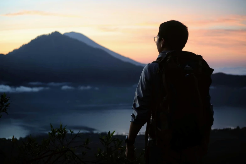 a man standing on a hill while the sun is setting