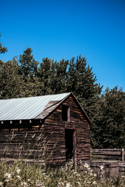 a wooden barn sitting in the middle of some grass