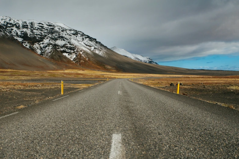 the road runs through the mountainous desert to meet the distant mountain range