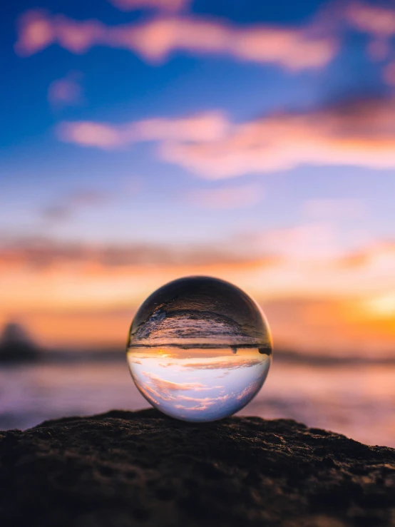 a glass ball on a beach with the sky in the background