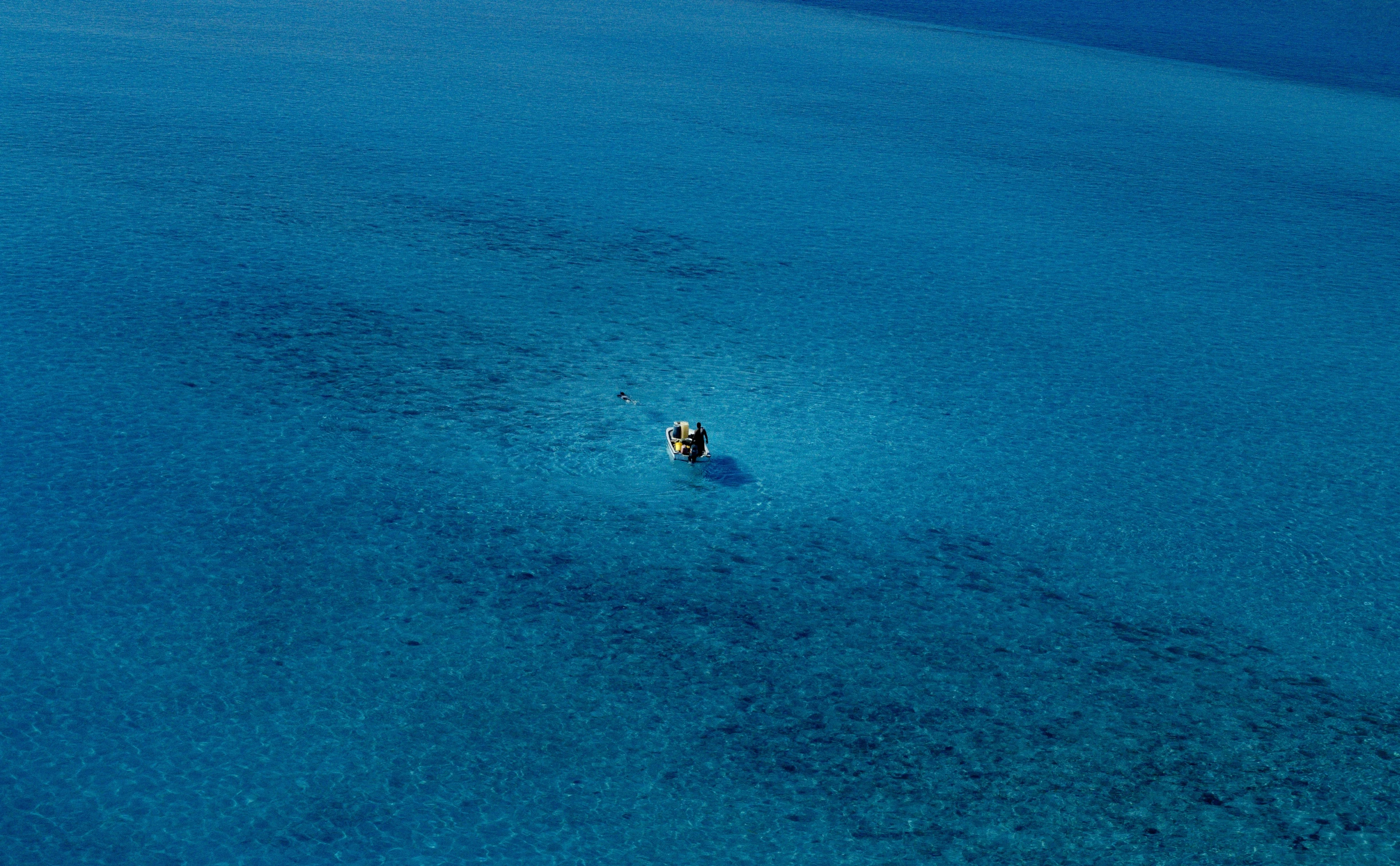 an aerial view of the ocean and people in their raft