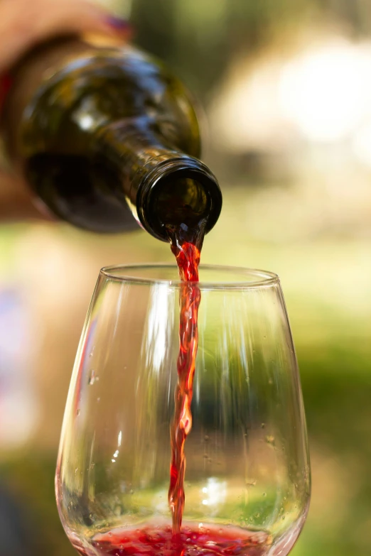 a wine glass filled with red liquid being poured into it