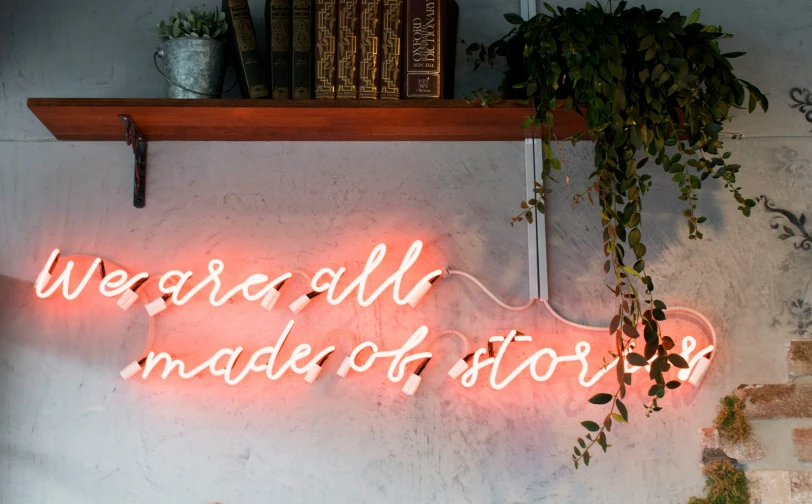 a neon sign on the side of a wall above a shelf