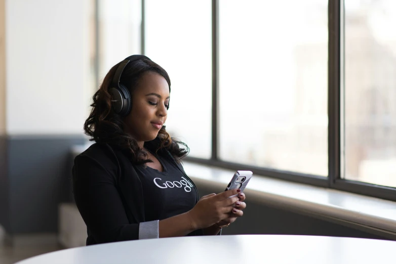 a woman sitting in a booth wearing headphones and looking at her cell phone