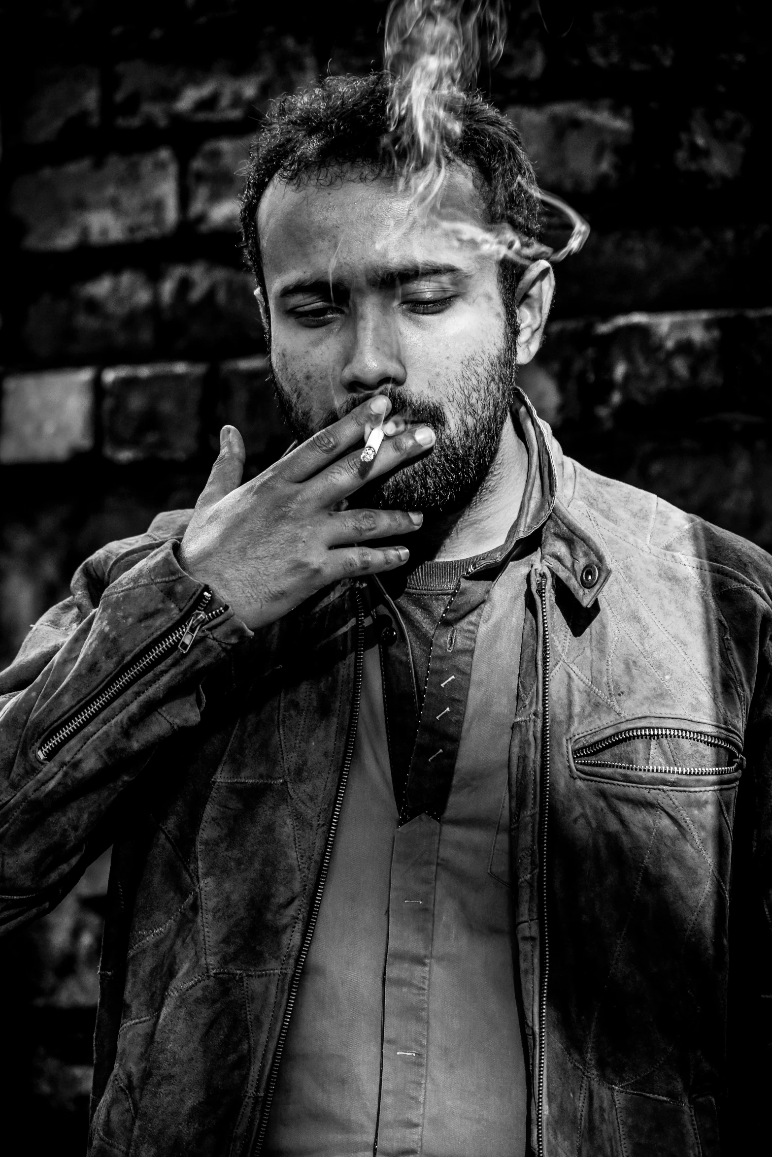 man smoking cigarette with a brick wall in the background