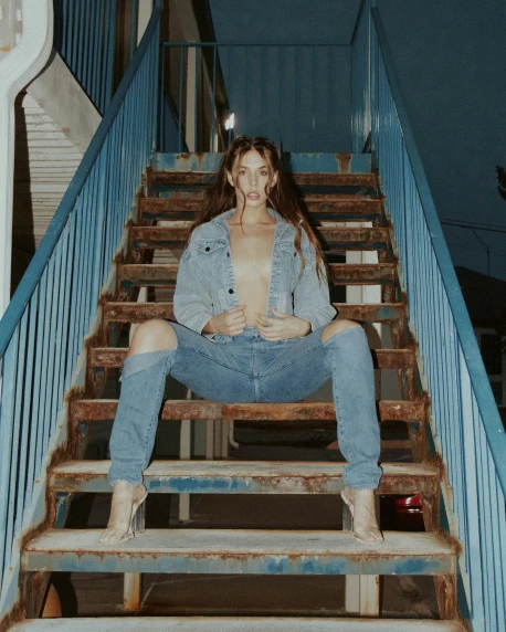 a woman is posing with her shirt on on a staircase