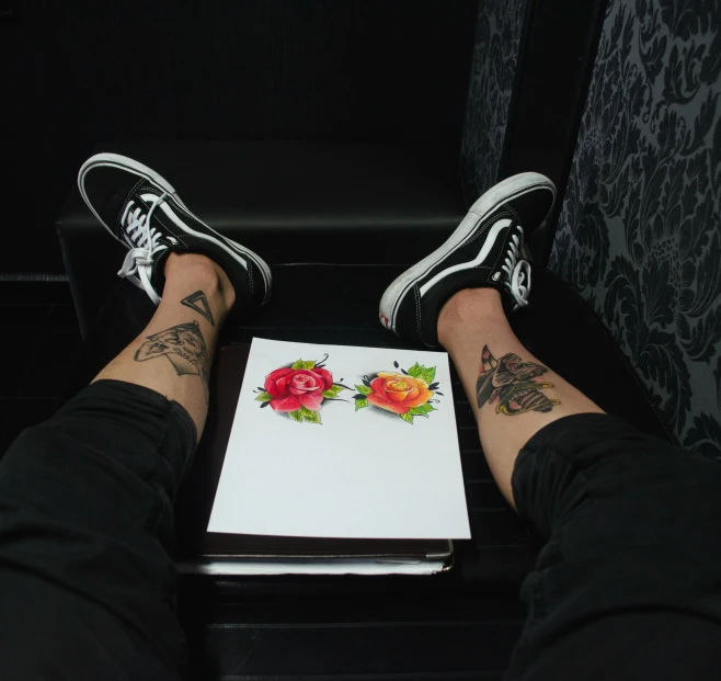 someone's legs with tattoos resting on top of a book