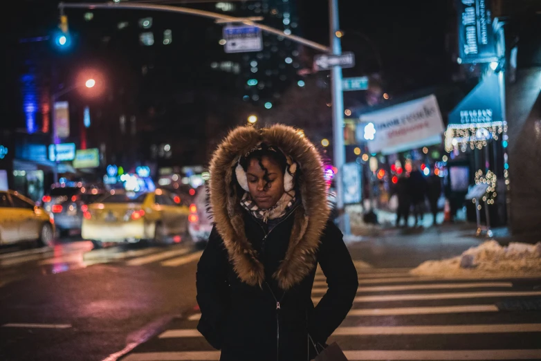 the woman is standing on the street corner at night