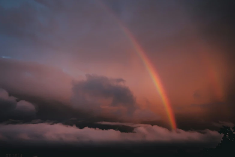 the cloud is very dark in the sunset with a rainbow