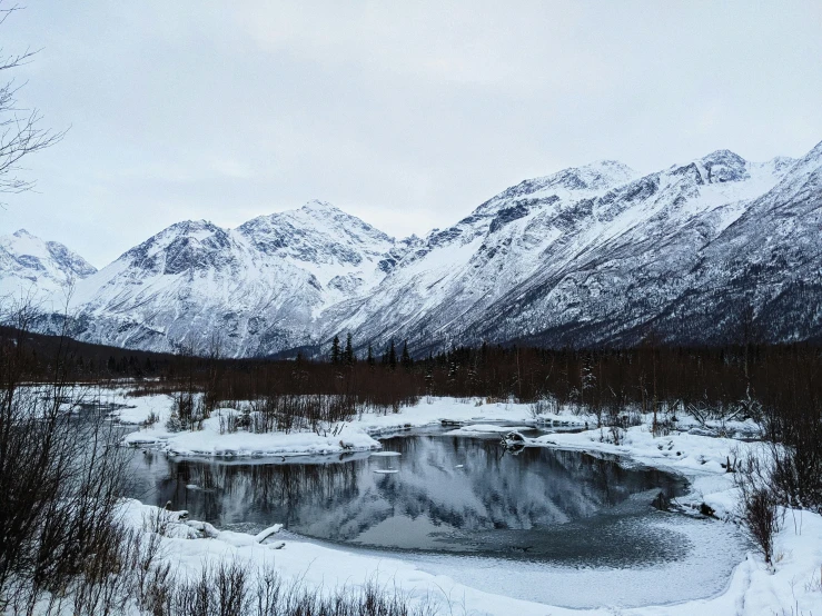 a snowy mountain range with a small lake