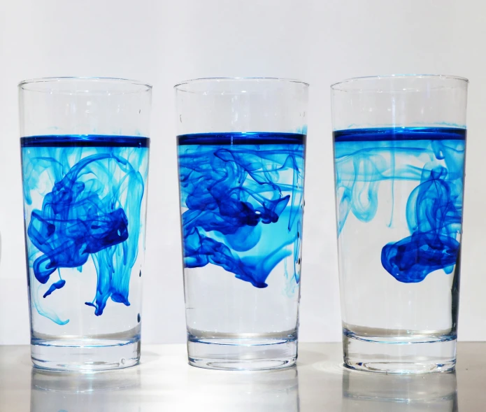 three glasses filled with different colors and shapes