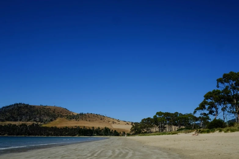 two people walk along the shore near an empty beach