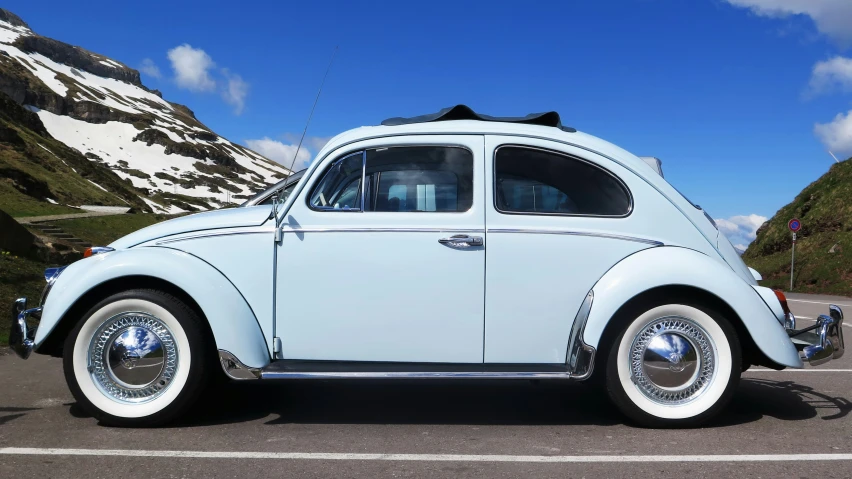 a blue vw bug sitting in a parking lot