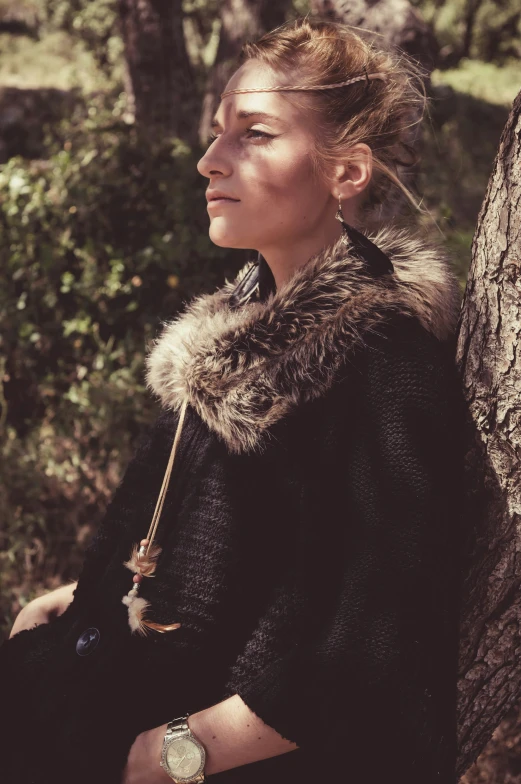 a girl is leaning against a tree, wearing a fur collar