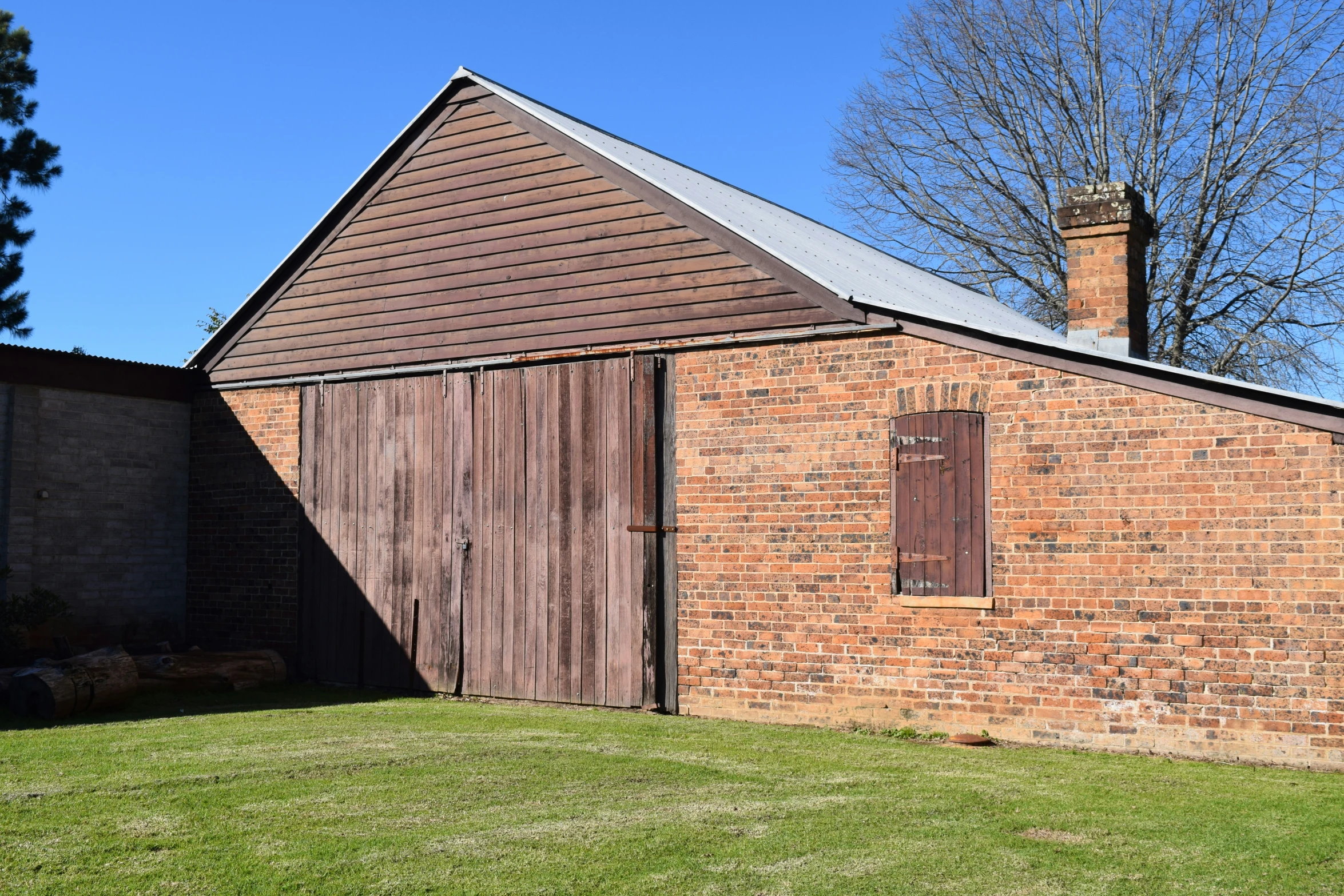 an old barn building next to a brick wall